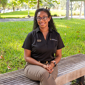 Tahnee Wilder sits on a bench outside the Education Complex, smiling.